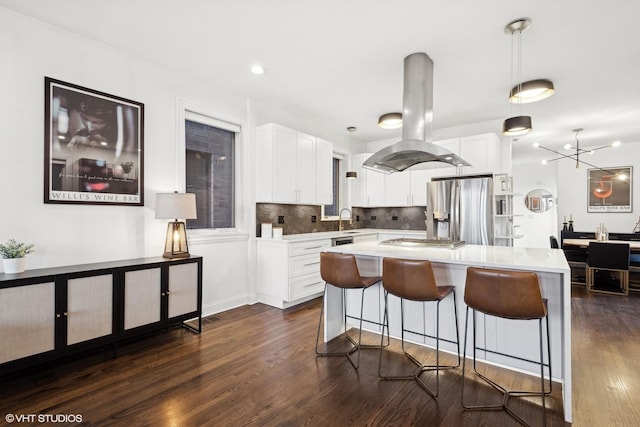 kitchen with pendant lighting, island range hood, stainless steel appliances, and white cabinets