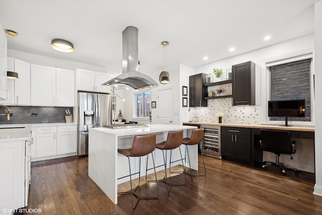 kitchen featuring stainless steel appliances, a center island, island range hood, white cabinets, and beverage cooler