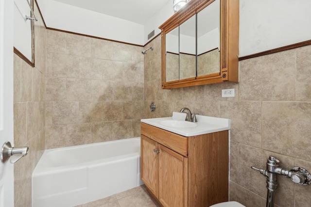 bathroom with tile patterned floors, vanity, tiled shower / bath combo, and tile walls