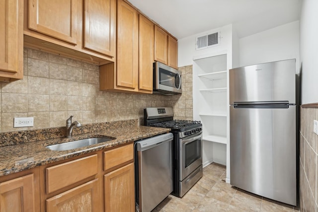 kitchen featuring tasteful backsplash, sink, stainless steel appliances, and dark stone counters