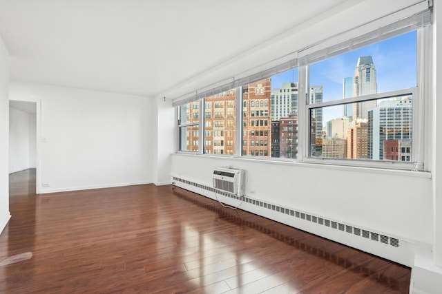 unfurnished room featuring a baseboard heating unit, a wall mounted air conditioner, a wealth of natural light, and wood-type flooring