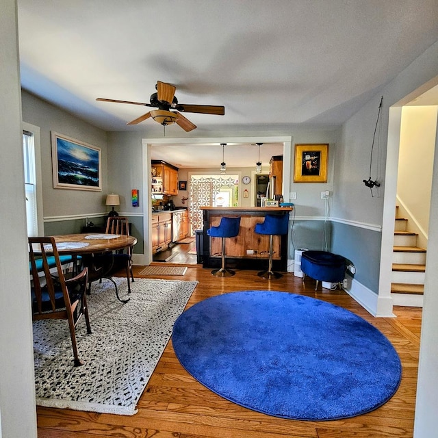 living room with ceiling fan, wood-type flooring, and bar area