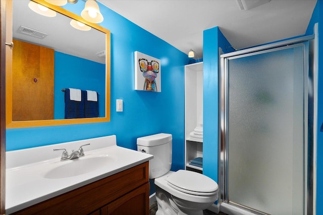 bathroom featuring toilet, a shower with door, and vanity