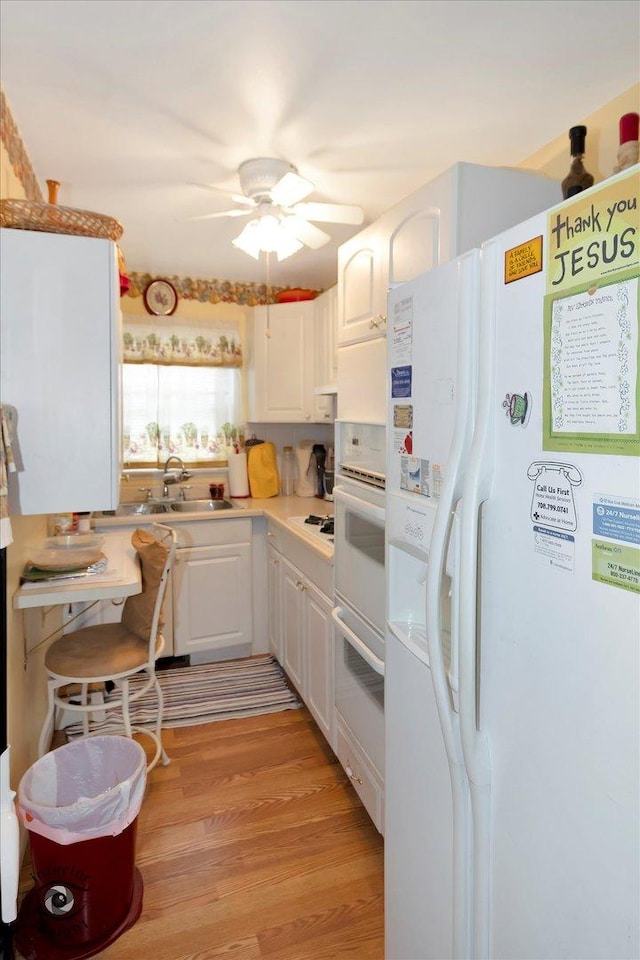 kitchen with sink, white appliances, white cabinets, and light hardwood / wood-style floors