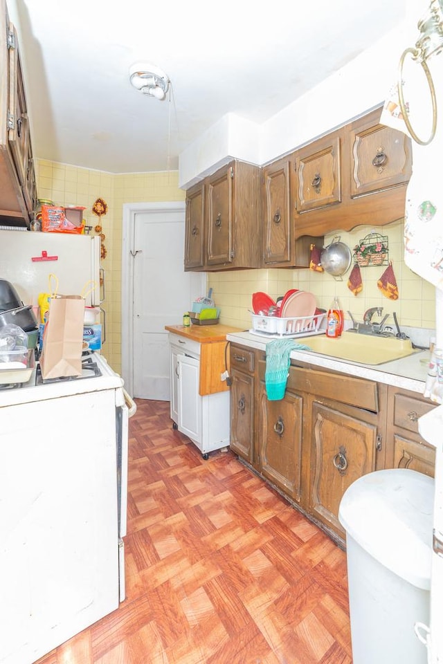 kitchen with sink, backsplash, white appliances, and light parquet floors