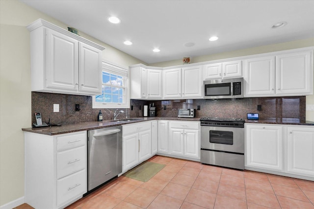 kitchen featuring sink, dark stone countertops, white cabinets, light tile patterned floors, and stainless steel appliances