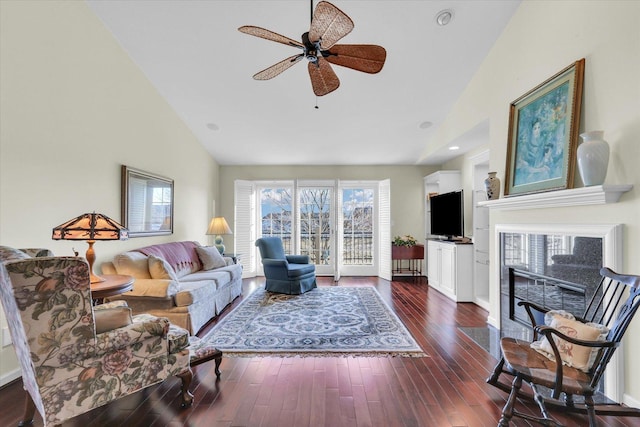 living room featuring dark wood-type flooring, ceiling fan, high vaulted ceiling, and a tile fireplace