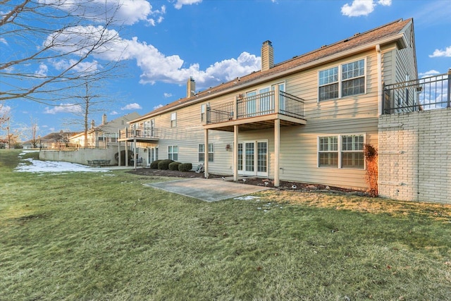 back of property with a patio, a balcony, and a lawn