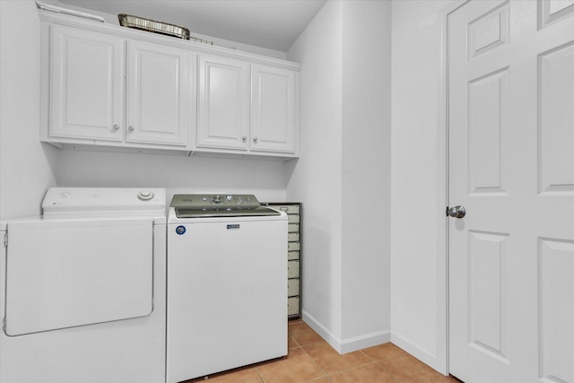 washroom with washer and clothes dryer, cabinets, and light tile patterned flooring