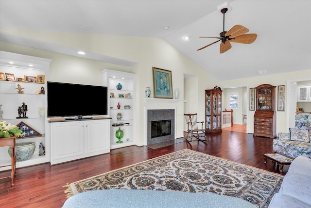 living room with lofted ceiling, dark wood-type flooring, ceiling fan, and built in shelves