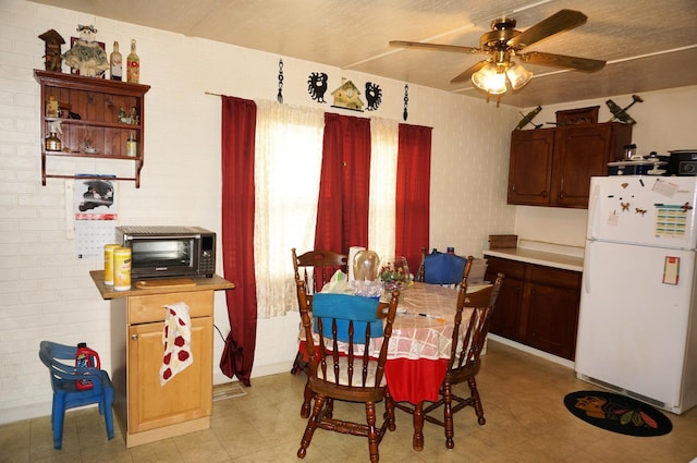 dining space featuring ceiling fan and brick wall