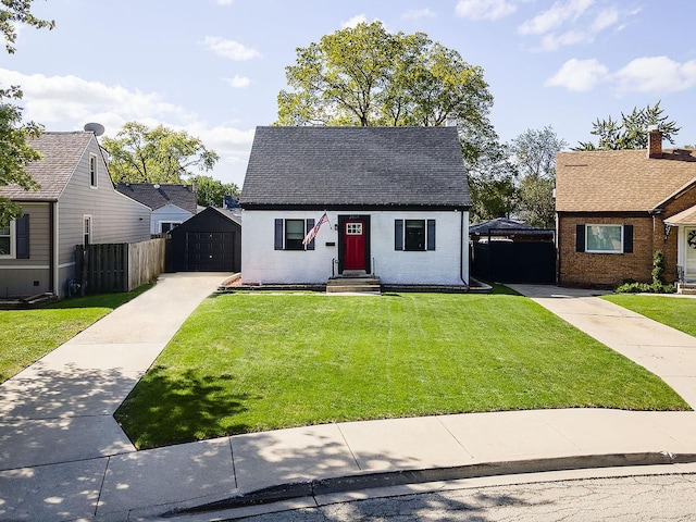 view of front facade with an outbuilding, a garage, and a front lawn