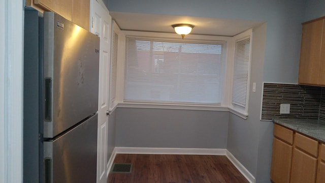 kitchen with stainless steel refrigerator, dark wood-type flooring, and backsplash