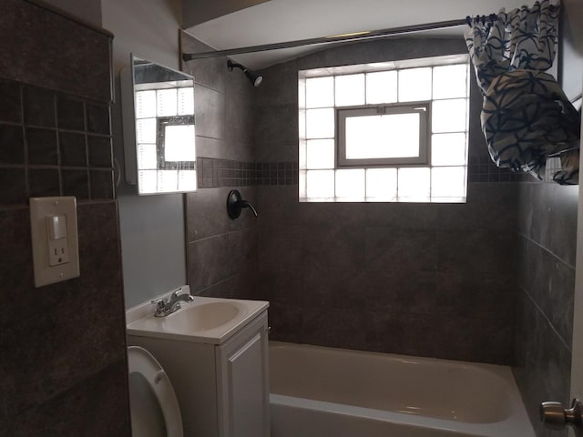 full bathroom featuring tiled shower / bath combo, vanity, and toilet