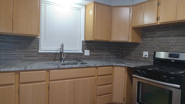 kitchen featuring backsplash, light brown cabinetry, sink, and stainless steel gas range oven