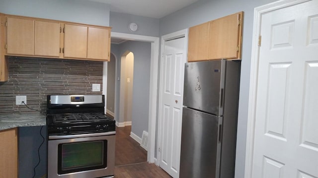 kitchen with appliances with stainless steel finishes, dark hardwood / wood-style floors, light brown cabinetry, and decorative backsplash