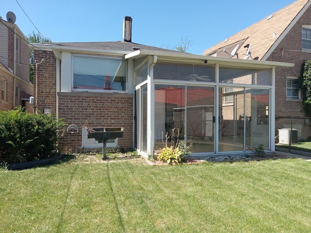 back of property with cooling unit, a lawn, and a sunroom