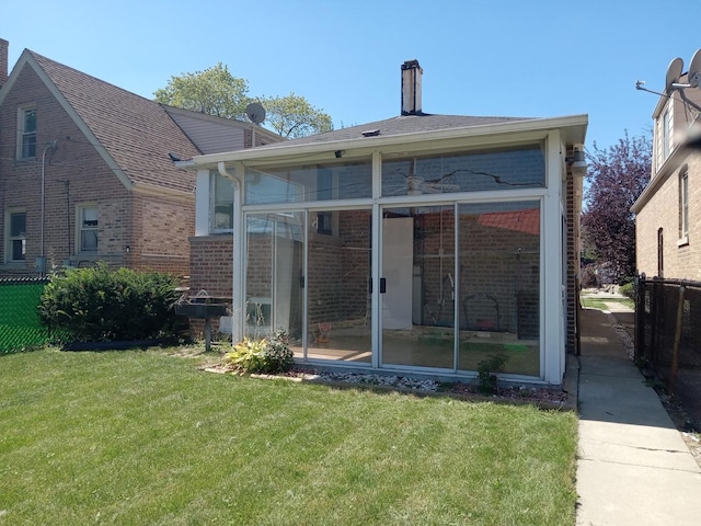 back of property with a sunroom and a yard