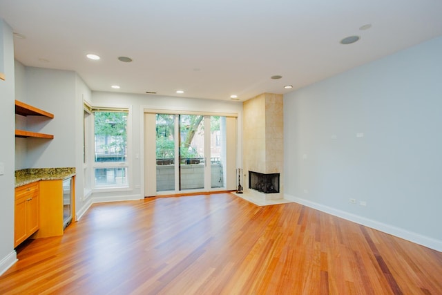 unfurnished living room featuring a multi sided fireplace and light hardwood / wood-style floors