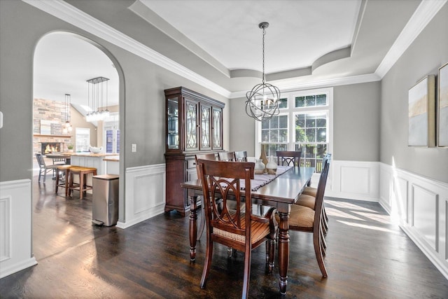 dining area featuring dark wood-type flooring, a tray ceiling, and an inviting chandelier