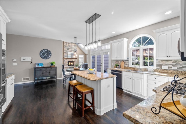 kitchen featuring stainless steel appliances, a fireplace, a center island, and white cabinets