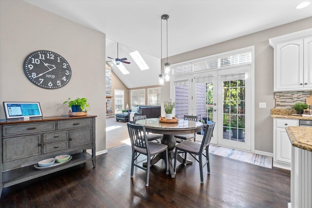 dining space with dark wood-type flooring, vaulted ceiling with skylight, and a healthy amount of sunlight