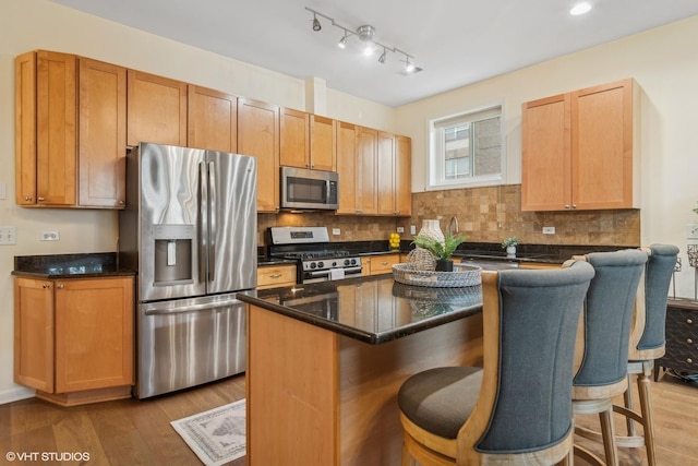 kitchen featuring appliances with stainless steel finishes, a center island, a kitchen breakfast bar, and light wood-type flooring