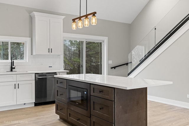 kitchen with white cabinets, black microwave, sink, backsplash, and stainless steel dishwasher