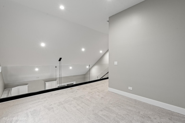 carpeted empty room with vaulted ceiling