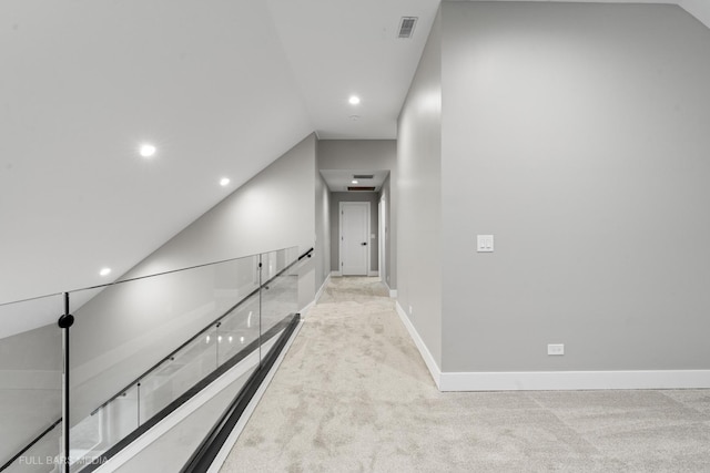 corridor with light colored carpet and lofted ceiling