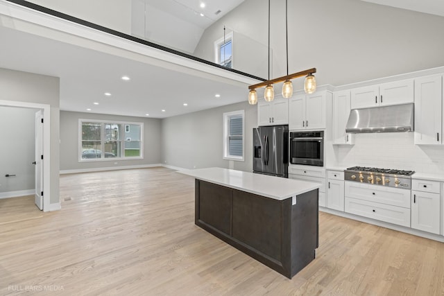 kitchen featuring decorative light fixtures, white cabinets, tasteful backsplash, high vaulted ceiling, and stainless steel appliances