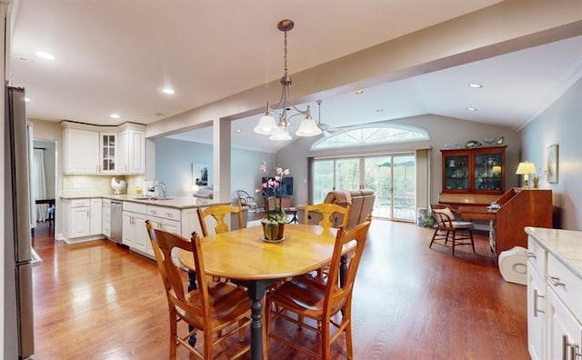 dining room featuring sink, lofted ceiling, a chandelier, and light hardwood / wood-style floors