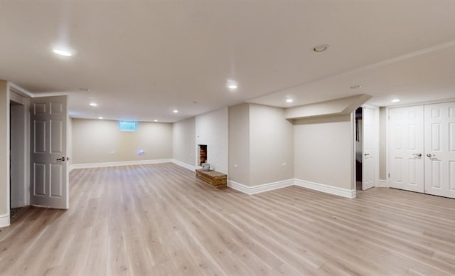 basement with light hardwood / wood-style flooring and a fireplace