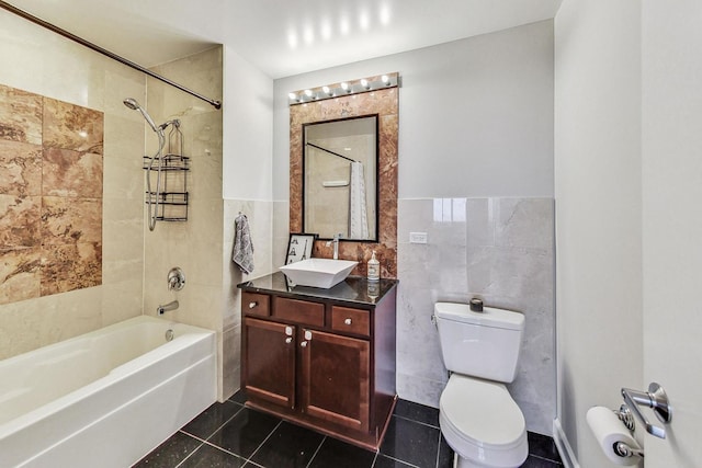 full bathroom with toilet, tile walls, tile patterned floors, vanity, and tiled shower / bath