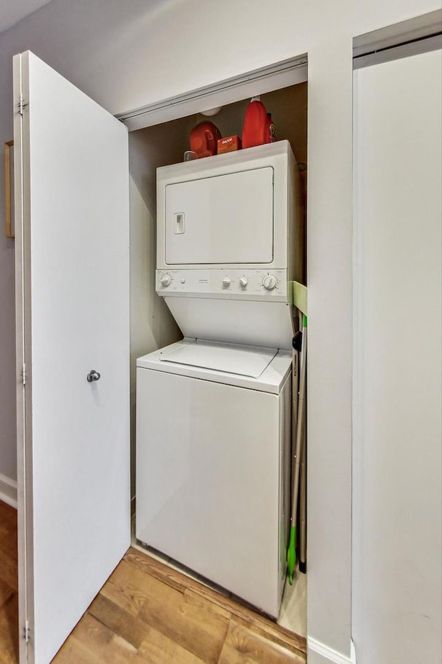 clothes washing area featuring light wood-type flooring and stacked washer / drying machine