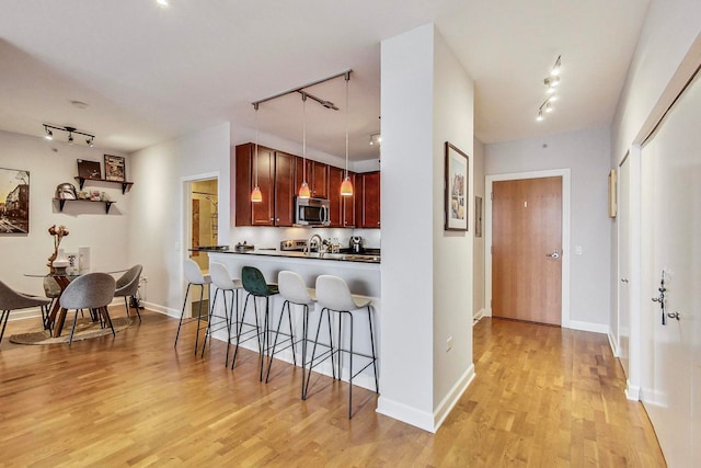 kitchen featuring light hardwood / wood-style floors, track lighting, kitchen peninsula, and a breakfast bar area