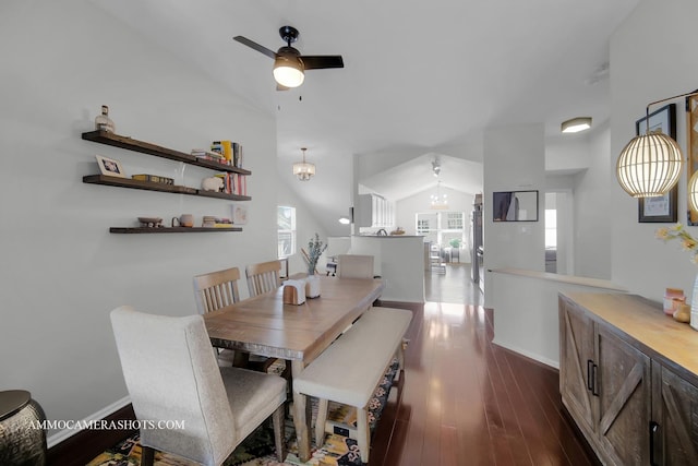 dining space with ceiling fan with notable chandelier, dark wood-type flooring, and vaulted ceiling