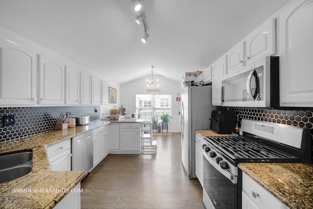 kitchen with lofted ceiling, appliances with stainless steel finishes, hanging light fixtures, and white cabinets