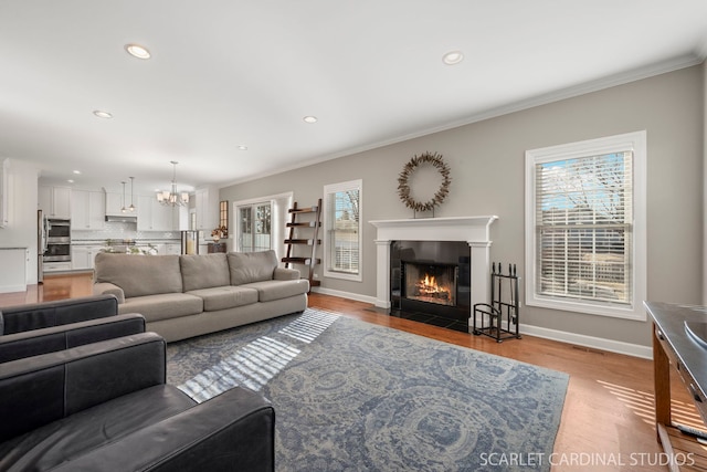 living room featuring hardwood / wood-style flooring, ornamental molding, and a chandelier