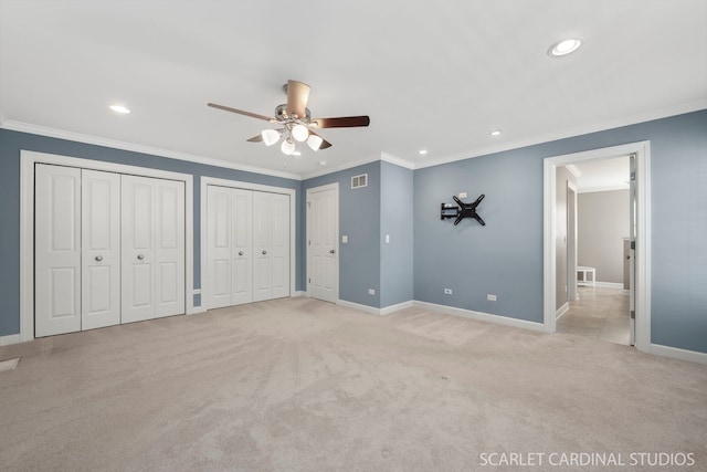 unfurnished bedroom featuring multiple closets, ceiling fan, ornamental molding, and light carpet