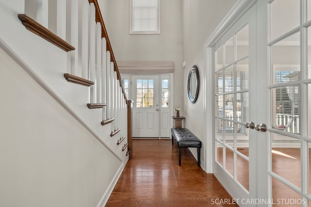 entrance foyer with french doors, a towering ceiling, and dark hardwood / wood-style flooring