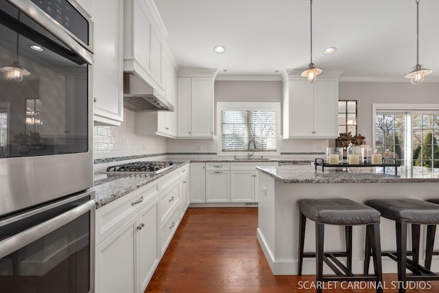 kitchen with a breakfast bar, white cabinetry, sink, stainless steel appliances, and light stone countertops