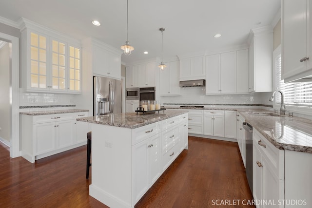 kitchen featuring sink, wall chimney range hood, appliances with stainless steel finishes, white cabinetry, and a center island