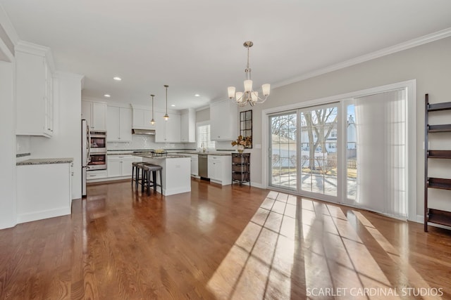 kitchen featuring a center island, hanging light fixtures, a kitchen breakfast bar, light hardwood / wood-style floors, and white cabinets