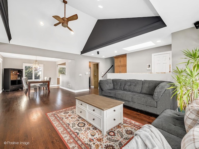 living room featuring dark hardwood / wood-style flooring, ceiling fan with notable chandelier, and lofted ceiling with skylight