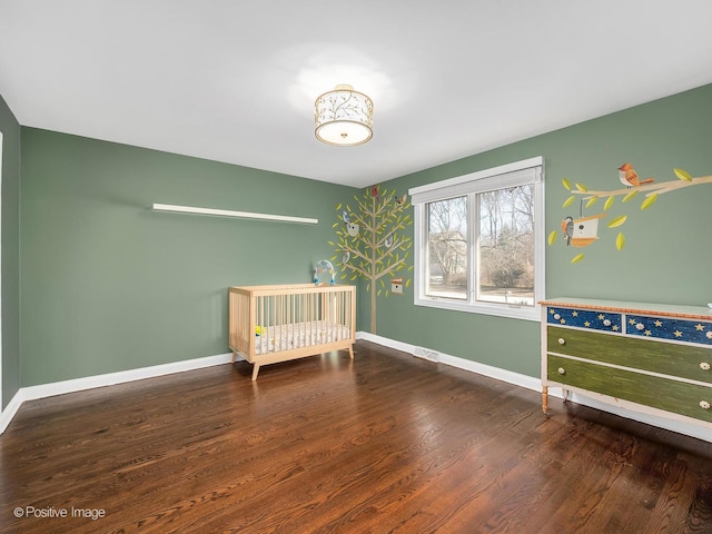 unfurnished bedroom with a crib and dark hardwood / wood-style floors