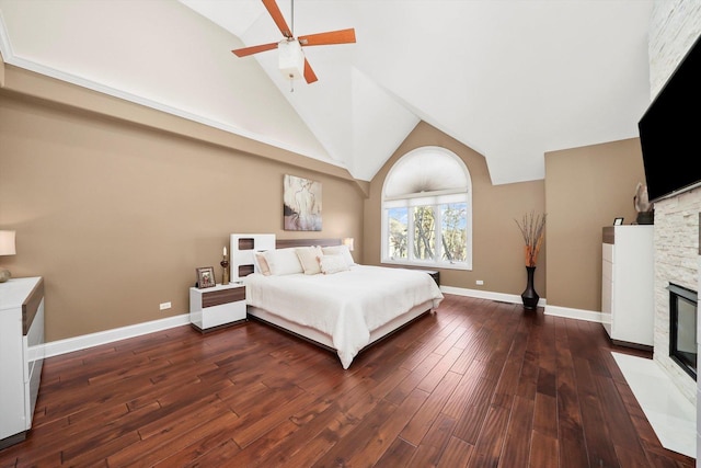 bedroom featuring ceiling fan, a stone fireplace, dark hardwood / wood-style flooring, and high vaulted ceiling