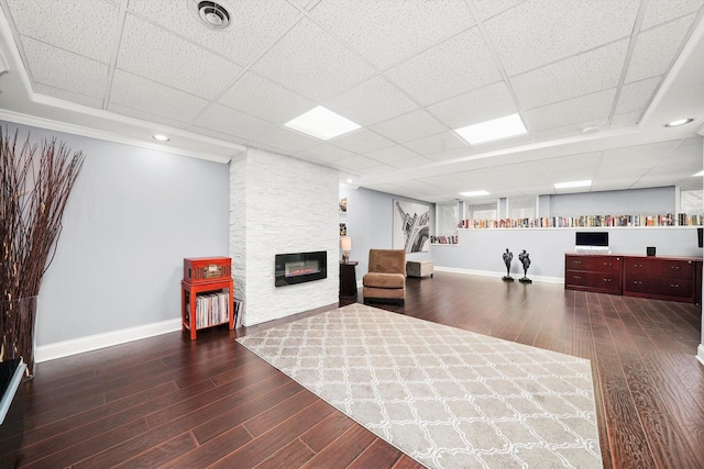 living area with dark hardwood / wood-style flooring, a paneled ceiling, and a fireplace