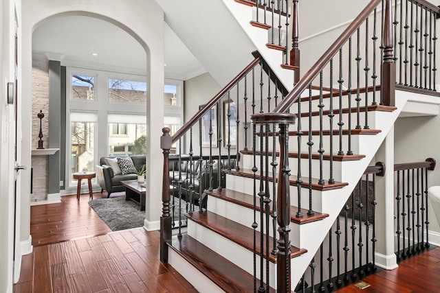 stairs featuring crown molding, wood-type flooring, and a high ceiling