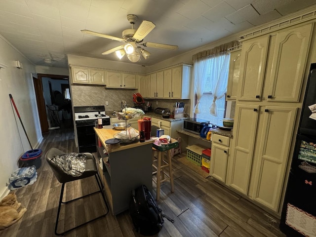 kitchen with backsplash, gas range oven, cream cabinets, and a breakfast bar